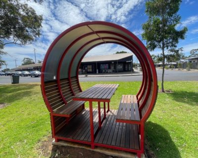 Back side of shaded bench which shows kiosk