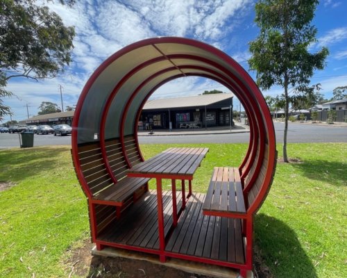 Back side of shaded bench which shows kiosk