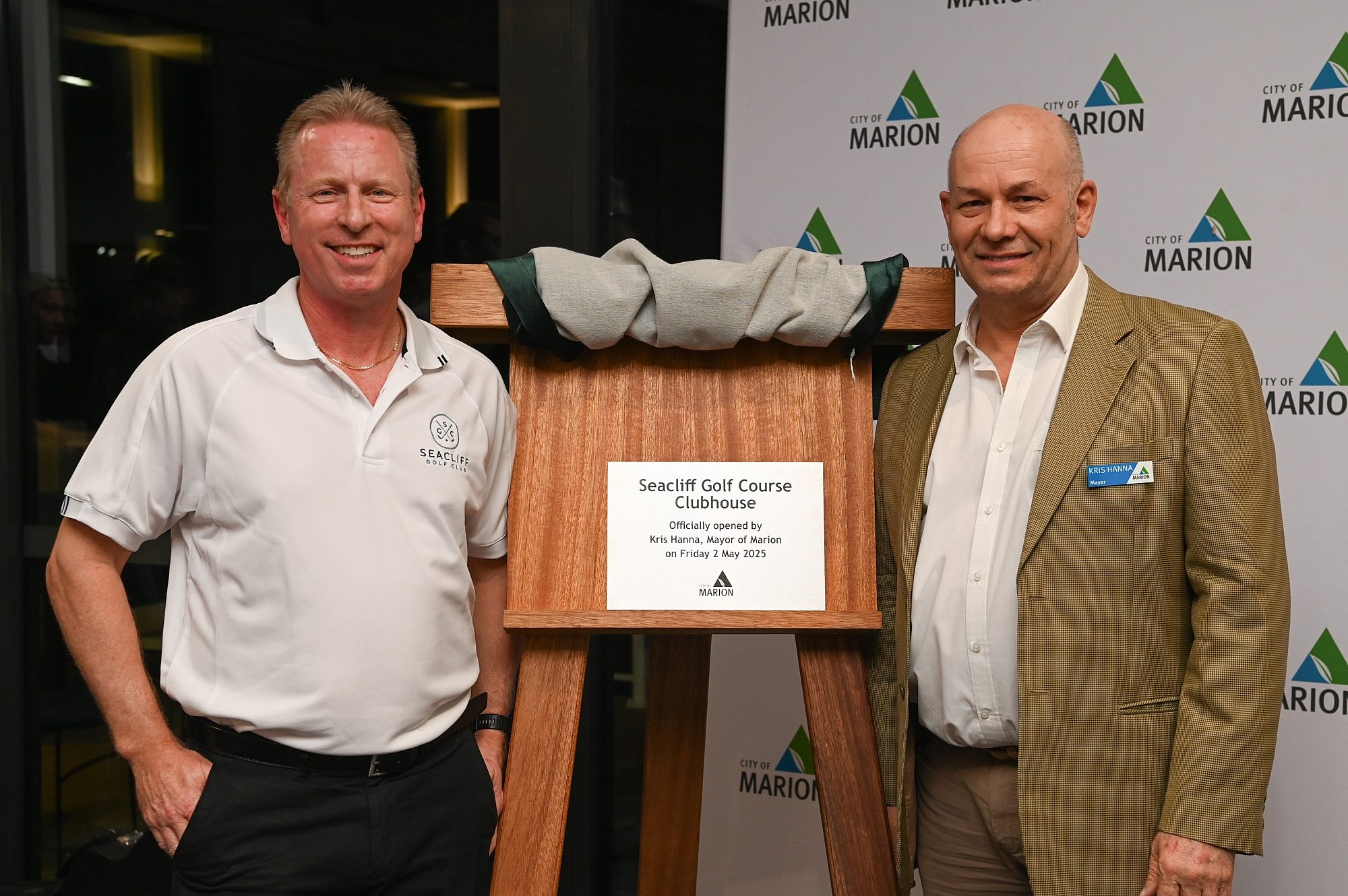 2 men stand aside of a unveiled plaque that says 'Seacliff Golf Course Clubhouse'